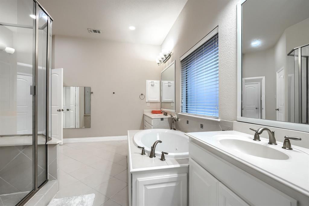 2246 Longview Road Irving, TX 75063 - Photo 22 of 40 Bathroom featuring a built-in soaking tub, dual vanities with integrated sinks, a glass-enclosed shower, and tiled flooring