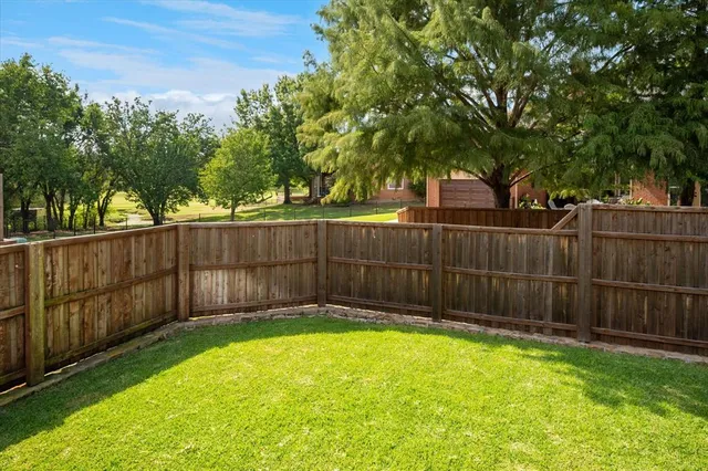 a view of a backyard with a large tree and wooden fence