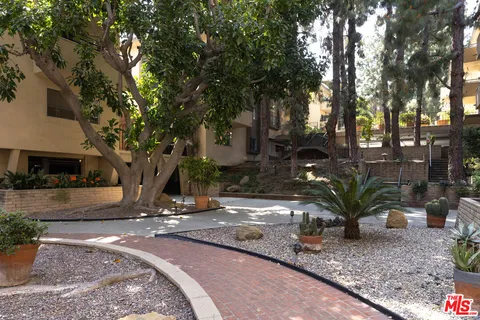 a view of a street with potted plants and large trees
