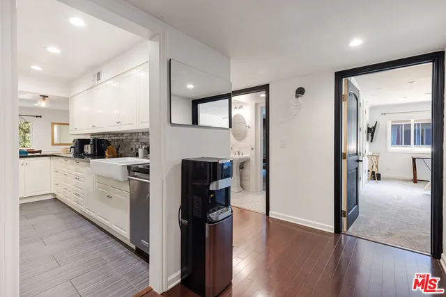 a kitchen with stainless steel appliances kitchen island granite countertop a refrigerator a sink and white cabinets with wooden floor