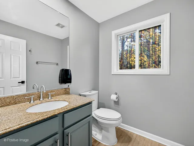 a bathroom with a granite countertop toilet a sink and a mirror