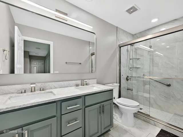 a bathroom with a double vanity sink toilet and shower
