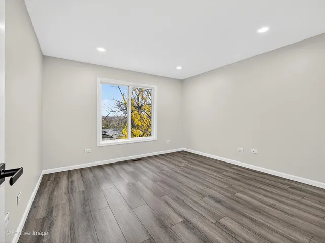 a view of an empty room with wooden floor and window