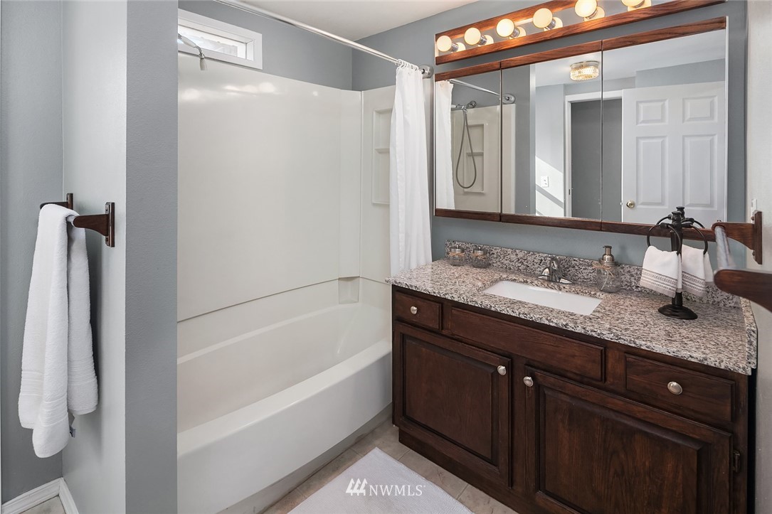 573 Bronson Place Northeast Renton, WA 98056 - Photo 18 of 32 a bathroom with a granite countertop sink mirror and a bathtub