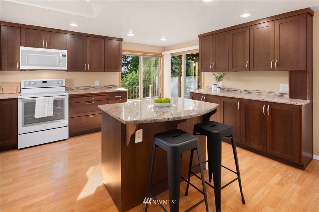 573 Bronson Place Northeast Renton, WA 98056 - Photo 7 of 32 a kitchen with granite countertop wooden cabinets dining table and chairs