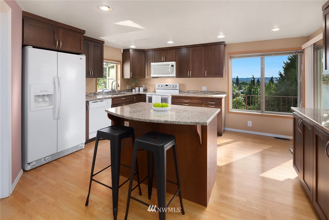 573 Bronson Place Northeast Renton, WA 98056 - Photo 8 of 32 a kitchen with stainless steel appliances granite countertop a refrigerator a stove a sink a dining table and chairs with wooden floor