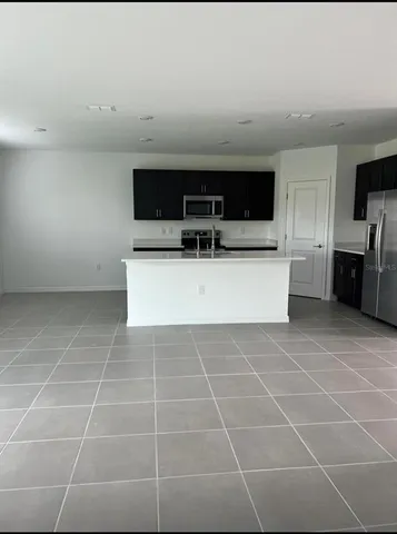 a living room with a furniture a flat screen tv and kitchen view