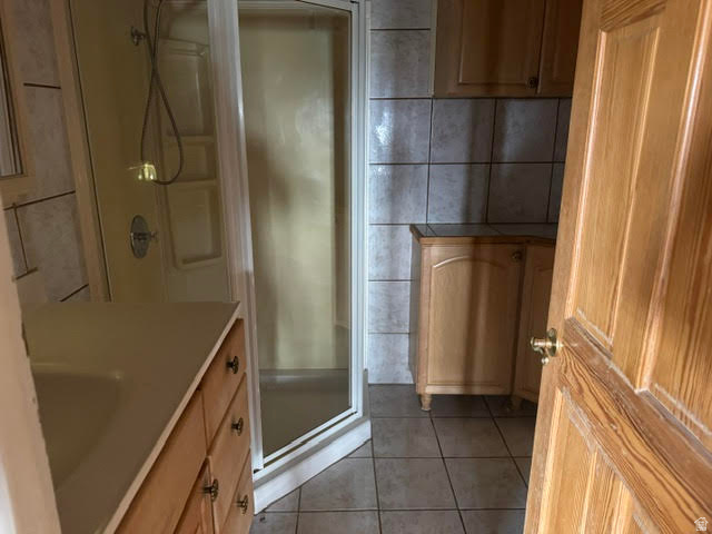 1124 Washam Road Green River, WY 82938 - Photo 22 of 35 Bathroom featuring a corner shower enclosure, light wood-finish vanity with an integrated sink, tile flooring, and wall tiling