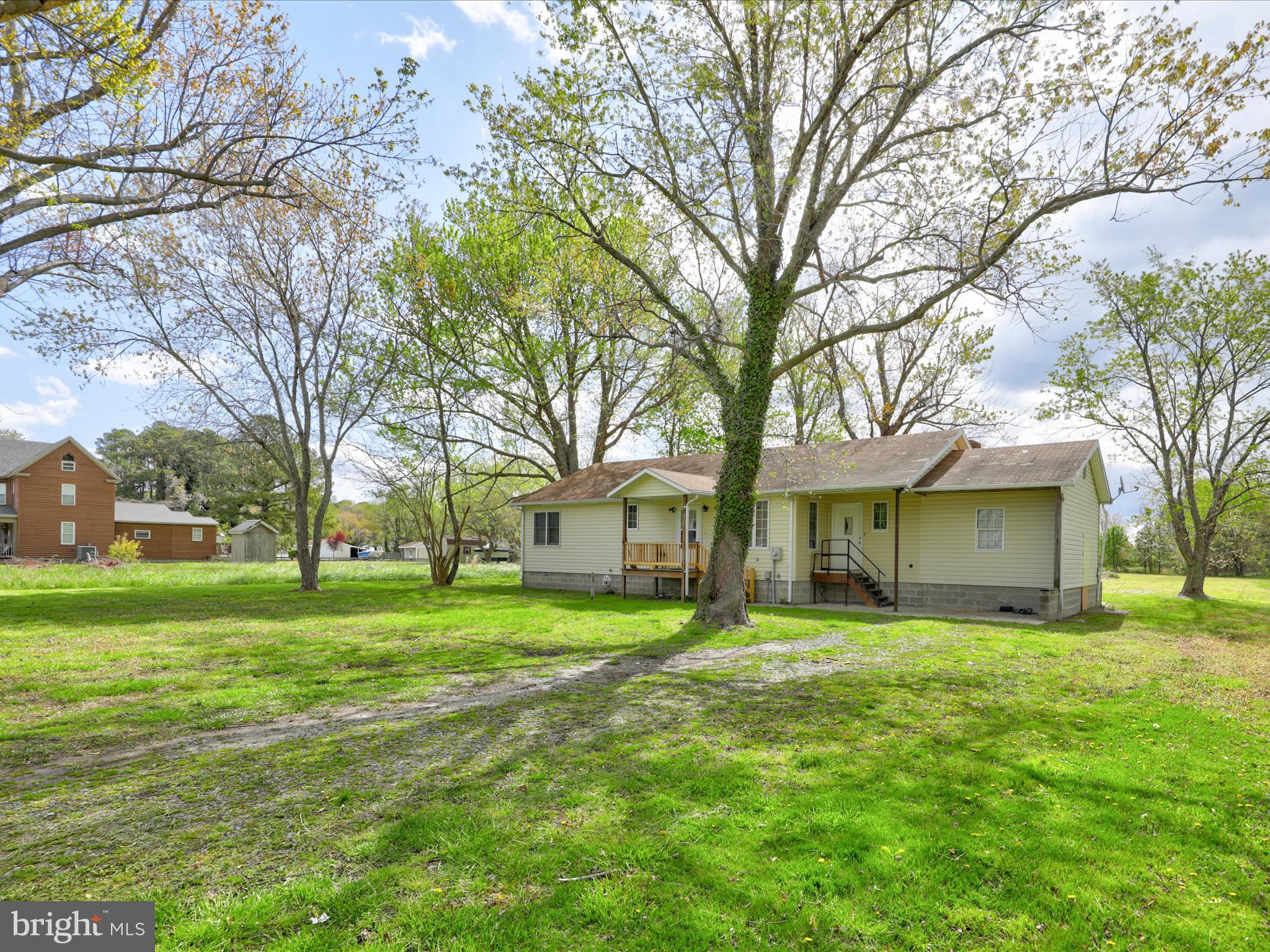 a brick house next to a yard with big trees