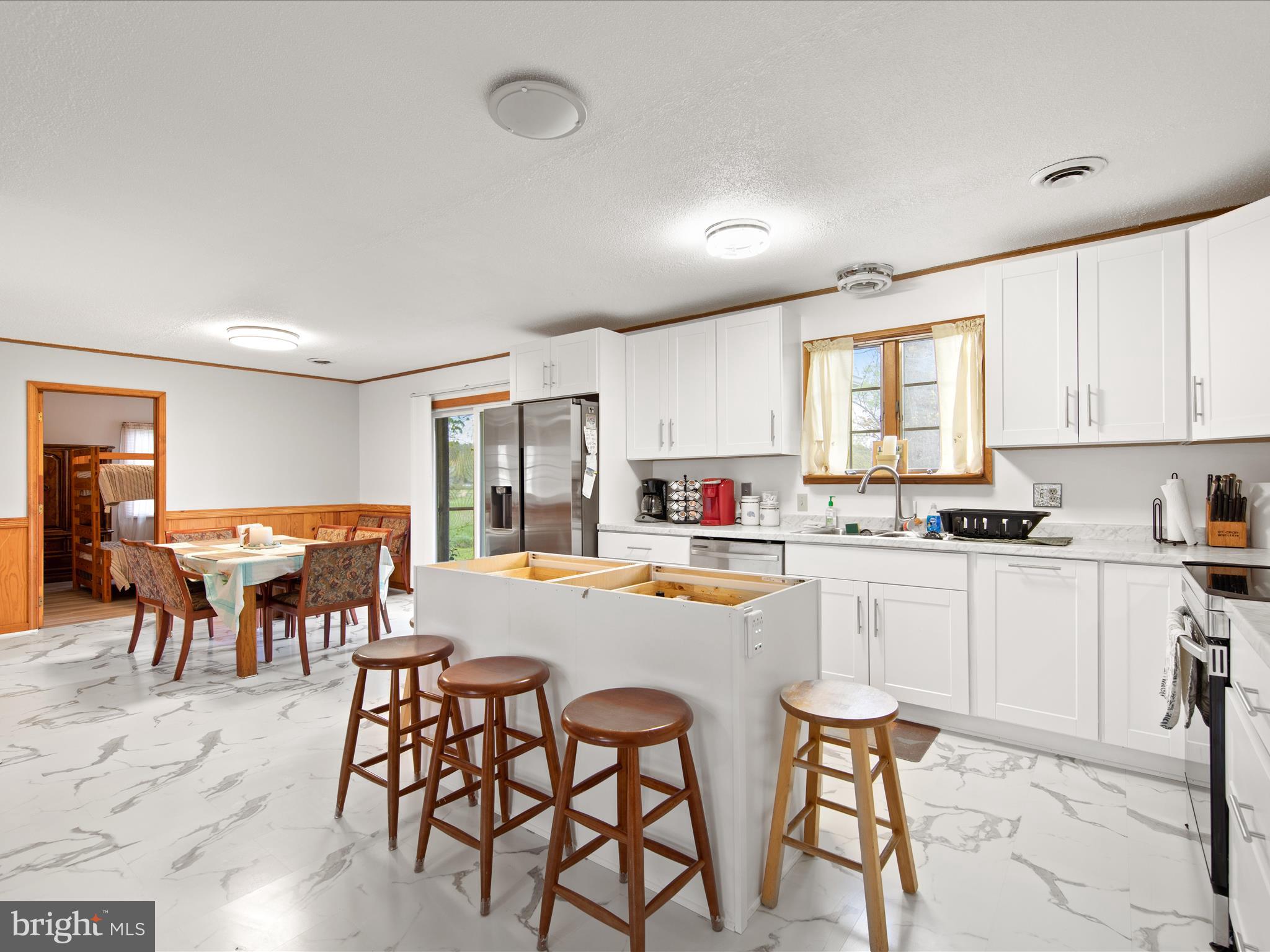23451 Deal Island Road Deal Island, MD 21821 - Photo 13 of 49 a kitchen with a dining table chairs sink and white appliances