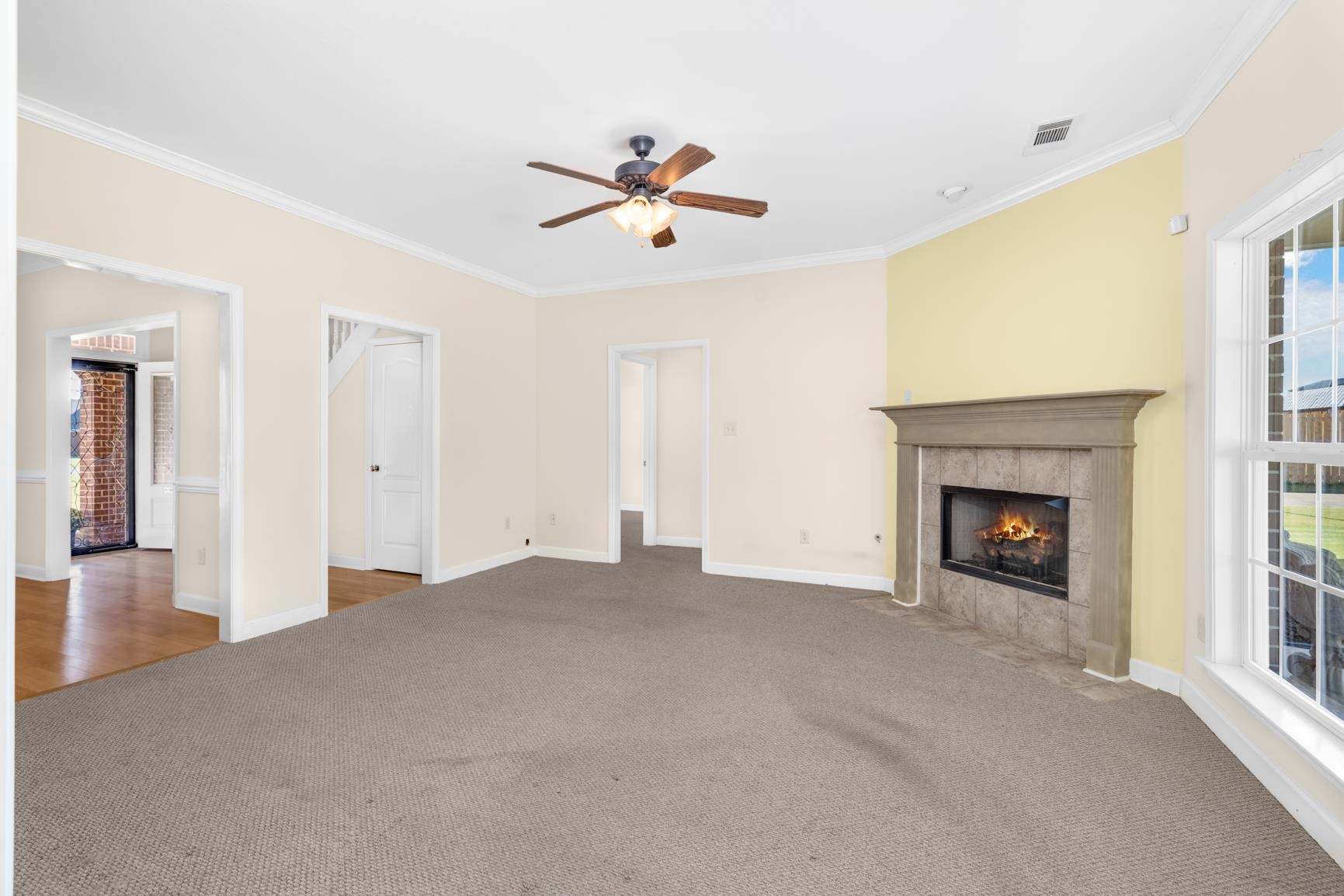 251 Rosemark Road Atoka, TN 38004 - Photo 17 of 40 Unfurnished living room with a tiled fireplace, crown molding, carpet, and ceiling fan