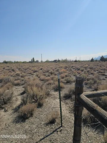 a view of a dry yard with wooden fence