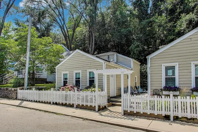 a view of a house with a small yard and large trees