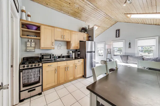 a kitchen with stainless steel appliances granite countertop a stove top oven a sink a dining table and chairs with white cabinets