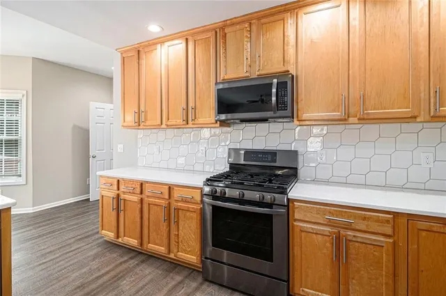 a kitchen with granite countertop a stove top oven microwave and cabinets
