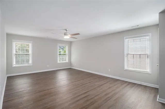 an empty room with wooden floor and windows