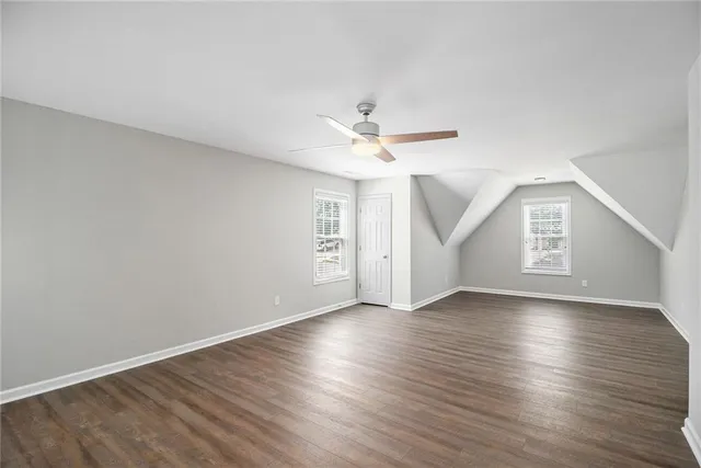 an empty room with wooden floor chandelier fan and windows