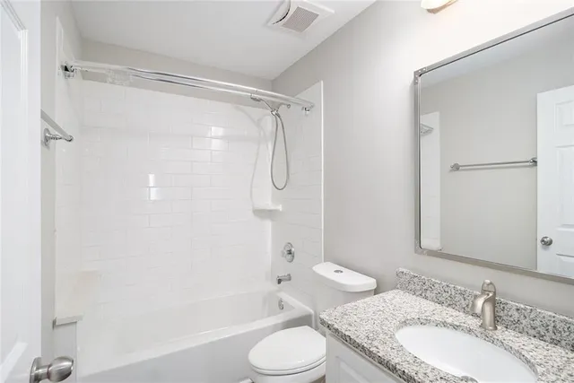 a bathroom with a granite countertop sink toilet and shower