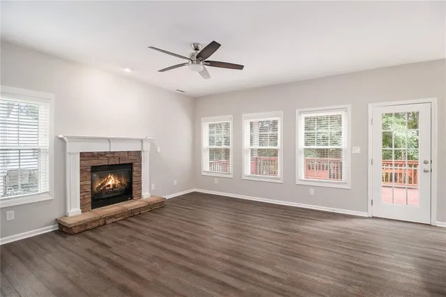 a view of an empty room with wooden floor fireplace and a window