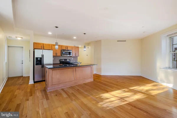 a kitchen with stainless steel appliances kitchen island granite countertop a refrigerator and a stove top oven