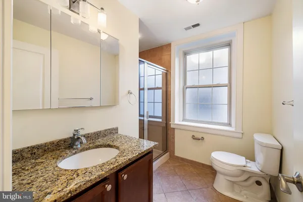 a bathroom with a granite countertop sink and mirror with bathtub