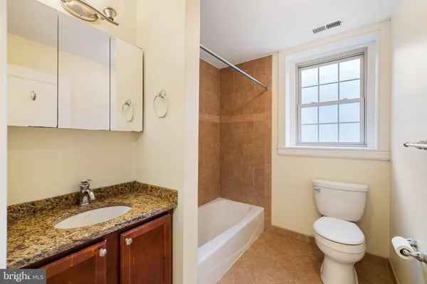 a bathroom with a granite countertop sink a toilet and bathtub