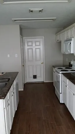 a kitchen with granite countertop a sink stove and cabinets