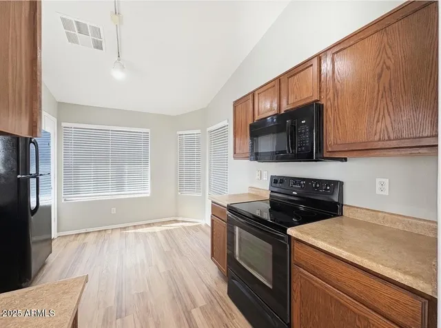 a kitchen with granite countertop wooden cabinets stainless steel appliances and a window