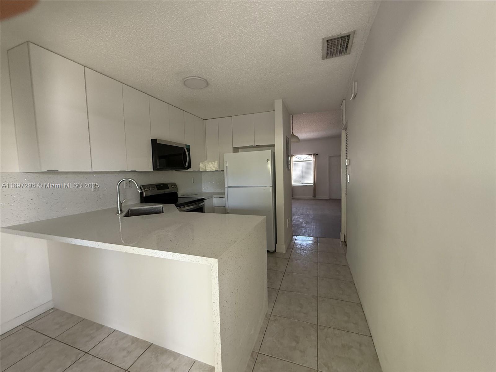 18942 Northwest 86th Court, Unit 4106 Hialeah, FL 33015 - Photo 6 of 10 a view of a hallway to a livingroom and a kitchen with furniture