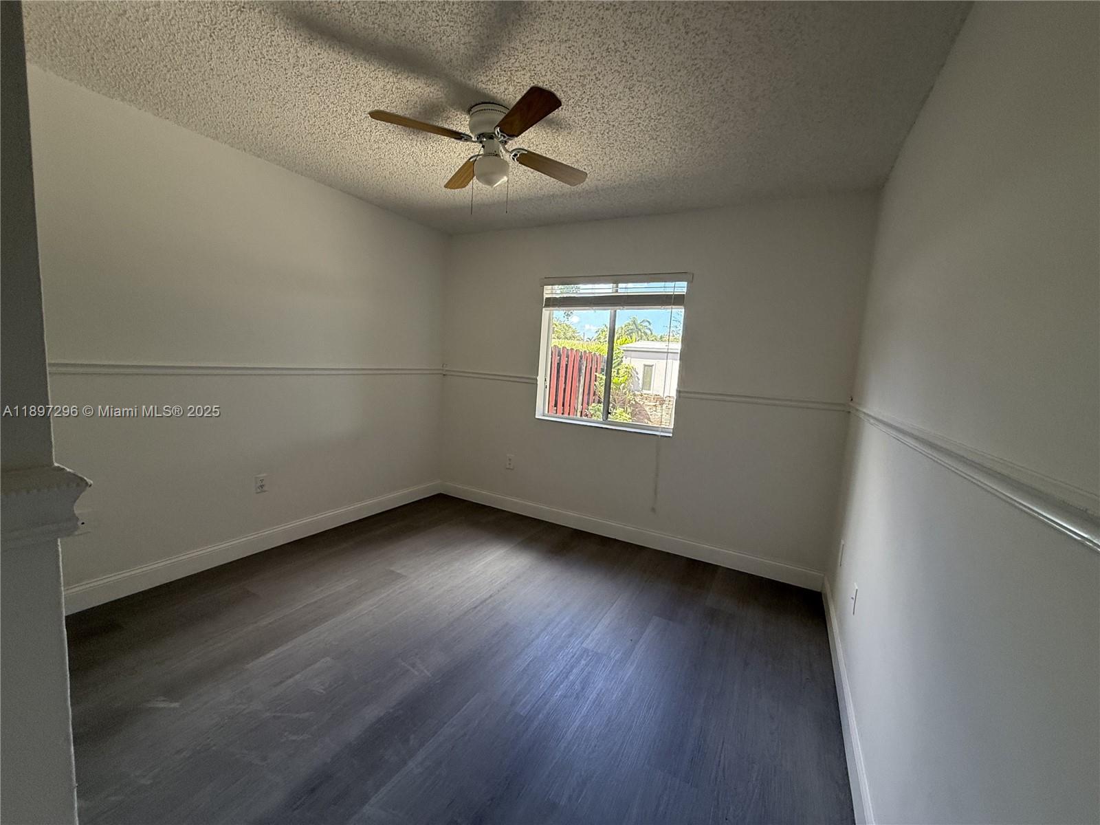 18942 Northwest 86th Court, Unit 4106 Hialeah, FL 33015 - Photo 7 of 10 an empty room with wooden floor fan and windows