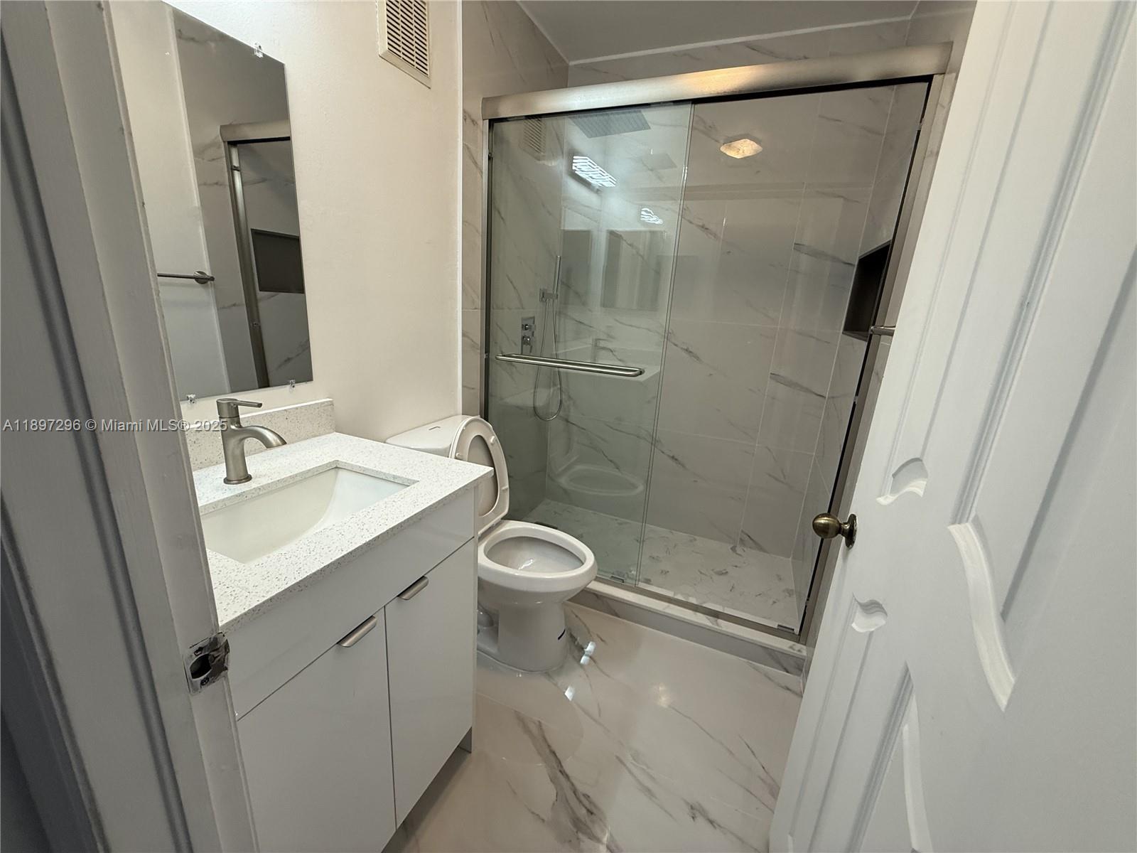 18942 Northwest 86th Court, Unit 4106 Hialeah, FL 33015 - Photo 9 of 10 a bathroom with a shower sink vanity and mirror