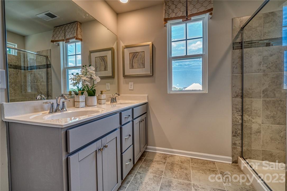 7020 Everly Commons Lane, Unit 2026 Tega Cay, SC 29708 - Photo 7 of 12 a bathroom with a granite countertop sink a mirror and a shower