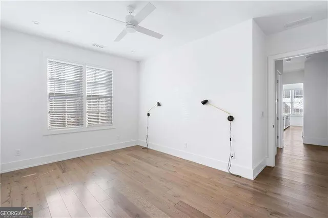 an empty room with wooden floor and windows