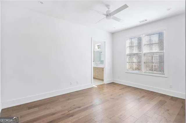 an empty room with wooden floor and fan