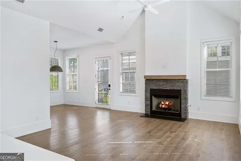 a view of an empty room with wooden floor fireplace and a window