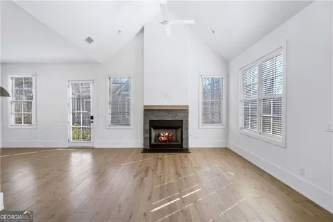a view of an empty room with wooden floor fireplace and a window