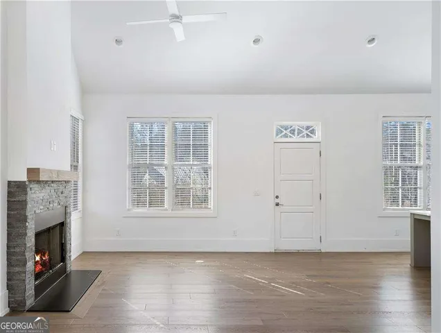 an empty room with windows fireplace and wooden floor
