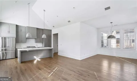 a large kitchen with stainless steel appliances a large counter top a stove a refrigerator and a view of living room