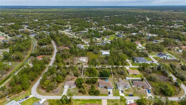 an aerial view of residential houses with outdoor space and trees