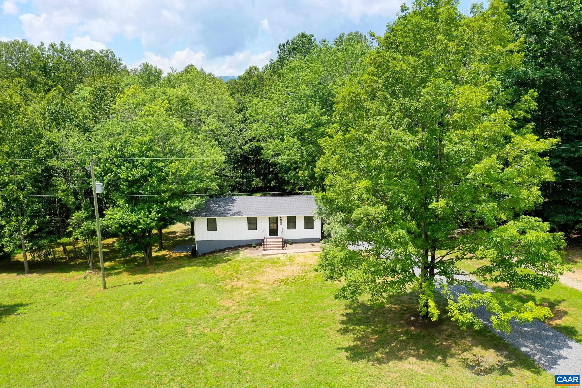a view of a house with a big yard and large trees