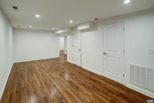 a view of empty room with wooden floor and fan