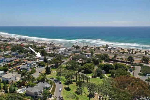 an aerial view of ocean and residential houses with outdoor space