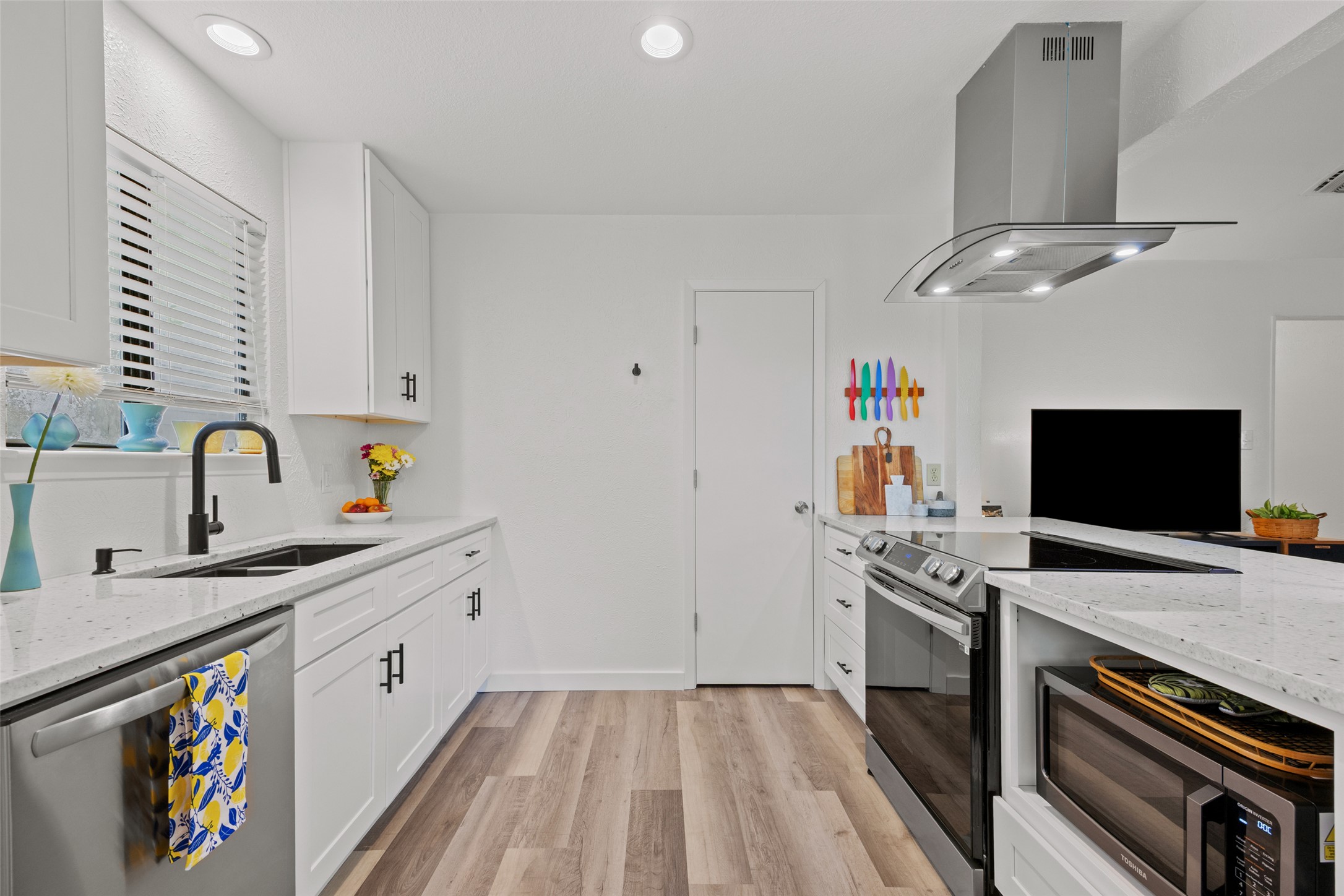 5506 South Pleasant Valley Road Austin, TX 78744 - Photo 6 of 25 A pristine culinary space with crisp white cabinetry and light wood-look flooring.