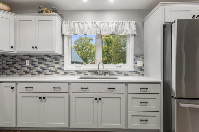 a kitchen with white cabinets and a window