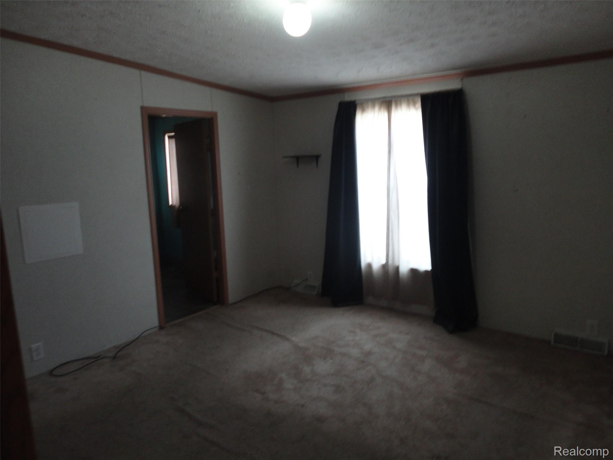 3954 Ryans Ridge Monroe, MI 48161 - Photo 15 of 28 Bedroom 1 featuring wall-to-wall carpeting, wood-trim paneling, and a large window with privacy sheers and blackout drapes