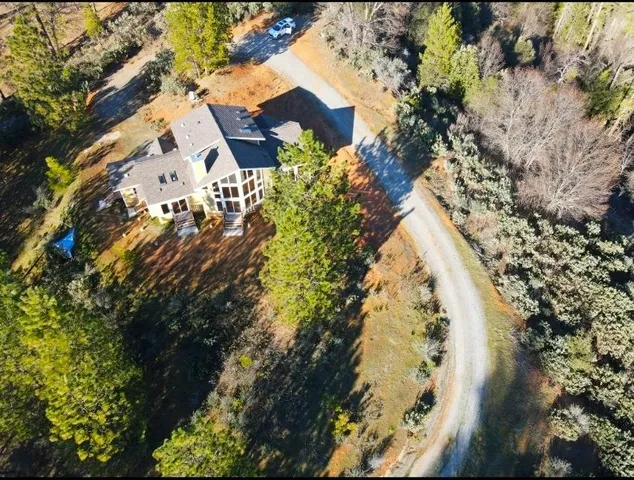 a view of a white house next to a yard with large trees