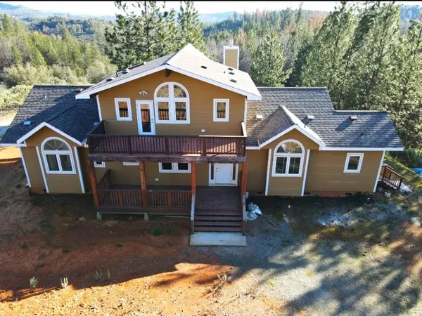an aerial view of a house with pool big yard and large trees
