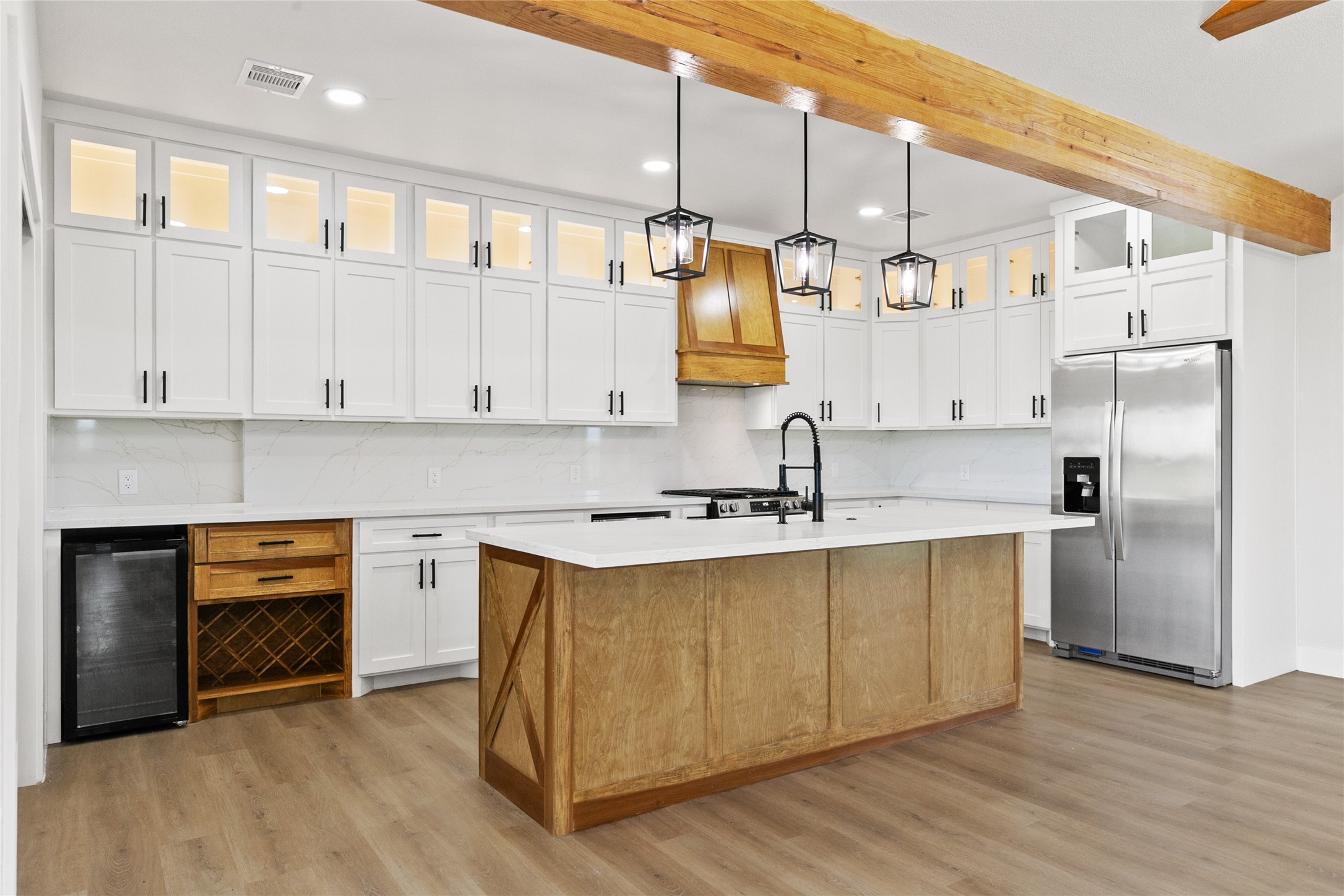 619 Chuckwagon Trail Angleton, TX 77515 - Photo 12 of 37 The kitchen blends style and function with quartz countertops, a wood island with an apron-front farmhouse sink, beverage refrigerator, wine storage, under-counter microwave, lighted glass-front cabinetry, and a large walk-in pantry.