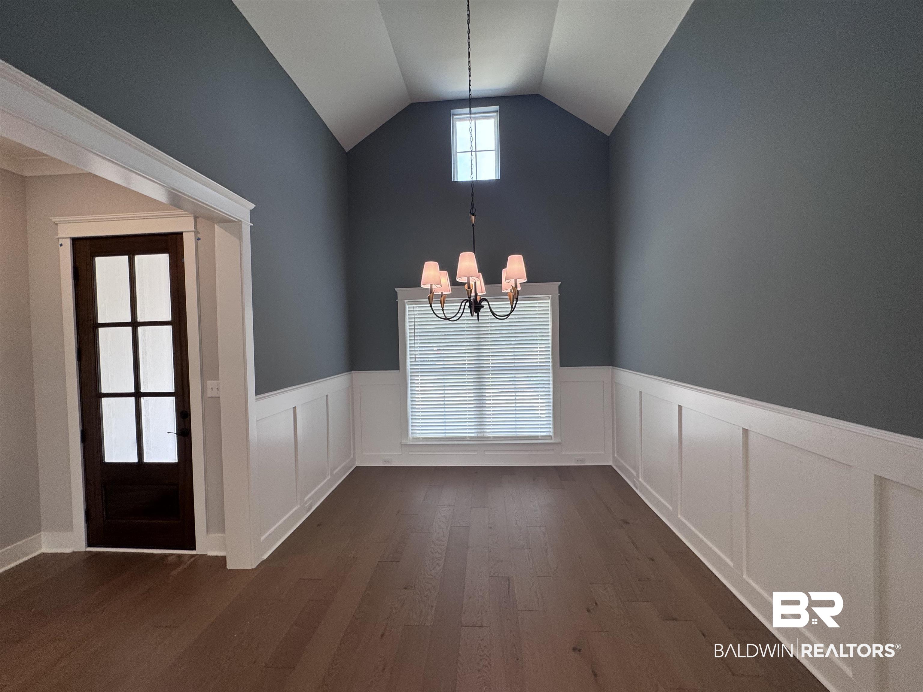 27371 Patch Pl Loop Daphne, AL 36526 - Photo 8 of 63 Unfurnished dining area with dark wood-style flooring, a wainscoted wall, a chandelier, and lofted ceiling