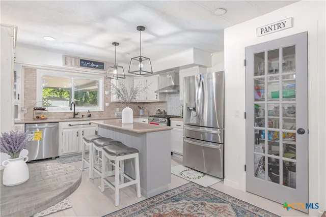 a kitchen with kitchen island granite countertop a sink cabinets and stainless steel appliances